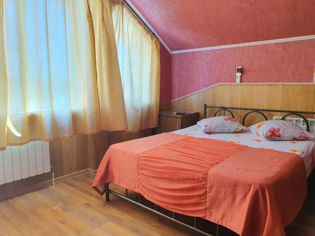 a bedroom with a bed with an orange blanket at Hotel Economy Classa Edelweiss in Nevinnomyssk