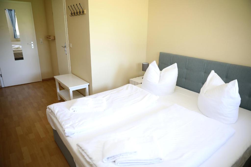 una camera da letto con letto, lenzuola e cuscini bianchi di Pension Elfmeter a Rheinsberg