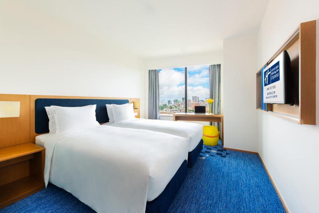 a hotel room with two beds and a flat screen tv at Holiday Inn Express Macau City Centre by IHG in Macau