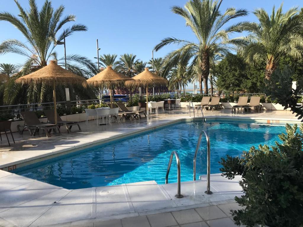 basen ze stołami, krzesłami i palmami w obiekcie Ohtels Gran Hotel Almeria w mieście Almería