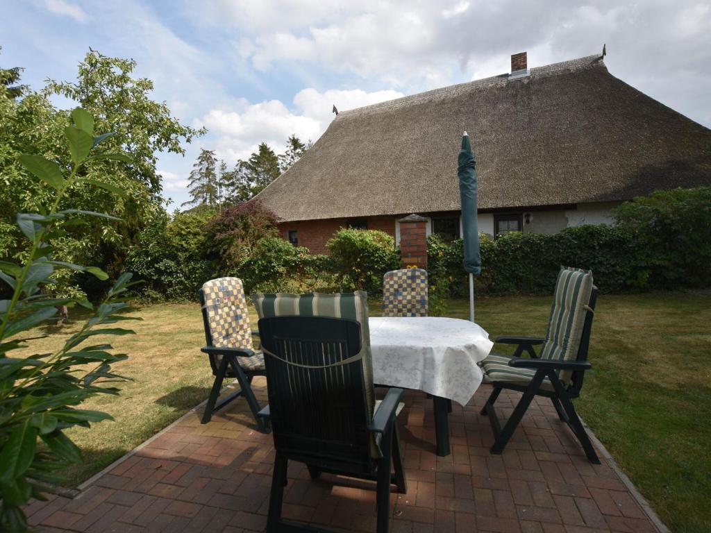 uma mesa com quatro cadeiras e uma casa com um telhado em Cozy Apartment in Alt Bukow Germany with Garden em Alt Bukow