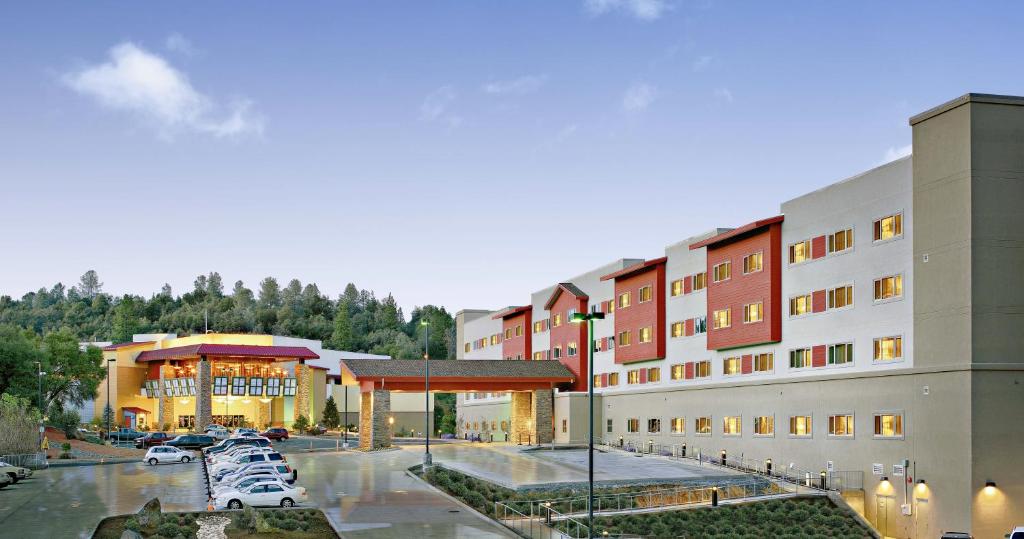 The Hotel at Black Oak Casino Resort في Tuolumne: مبنى كبير به سيارات تقف في موقف للسيارات