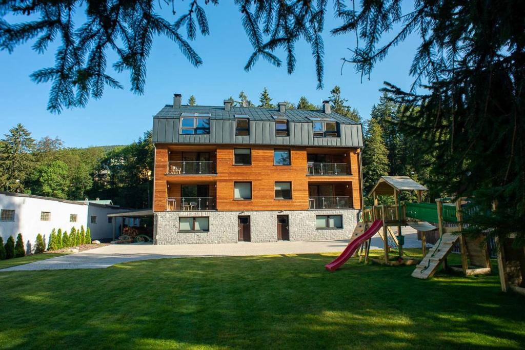 a large building with a playground in a yard at Apartmány Hromovka in Špindlerův Mlýn