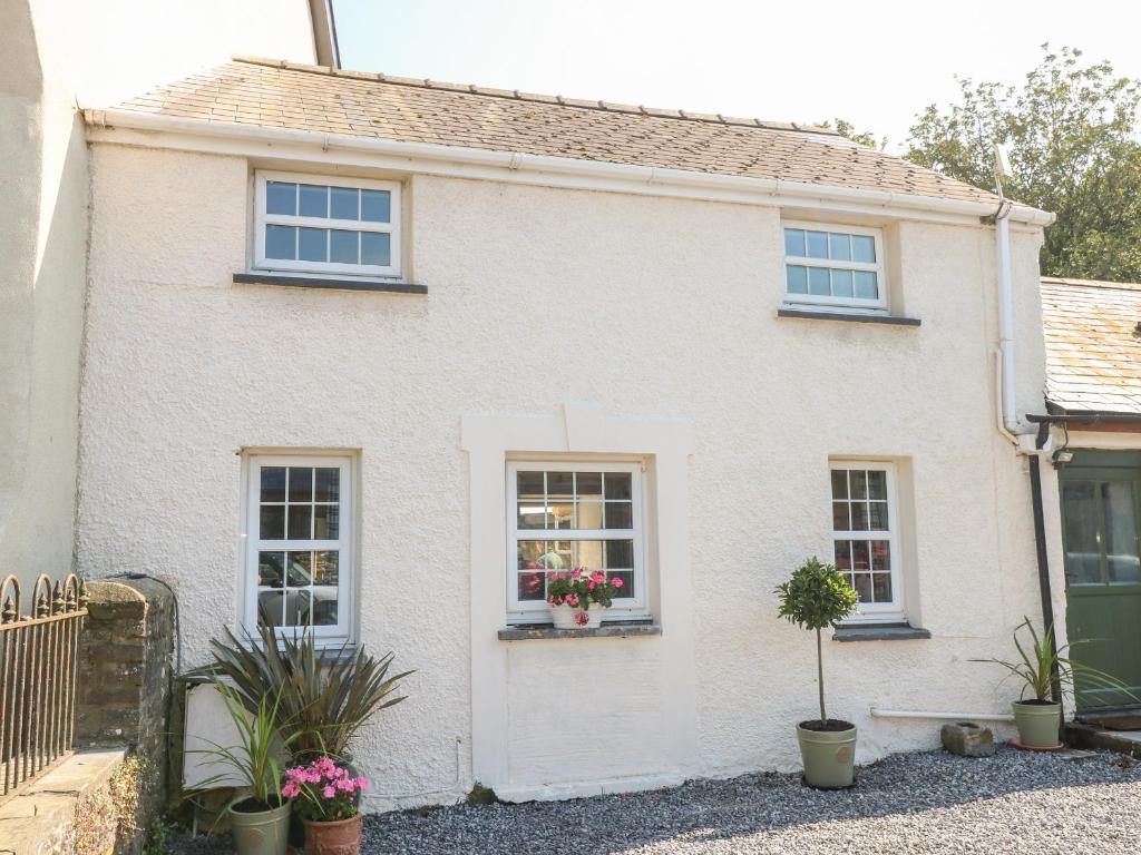 een wit huis met ramen en potplanten bij Garden Cottage in Haverfordwest