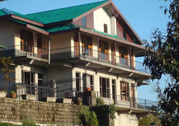 una grande casa con tetto verde in cima di Kora House a Dharamsala