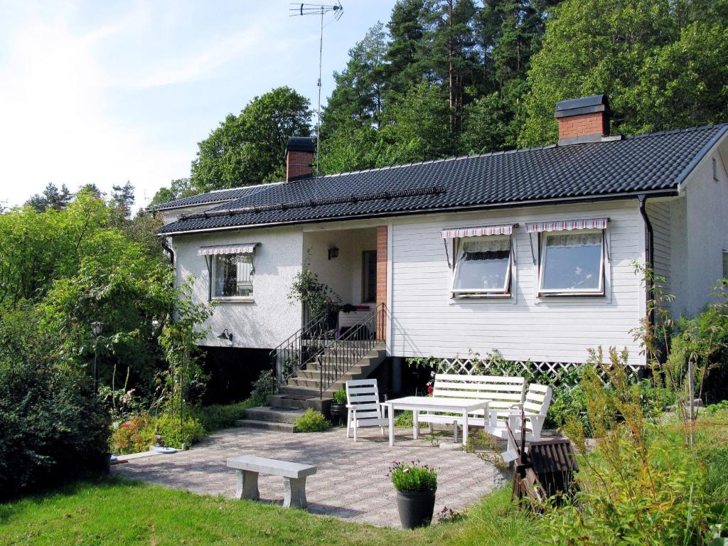 a white house with a table and chairs on a patio at Holiday Home Trollsjö Stegeborg - OST102 by Interhome in Norrkrog