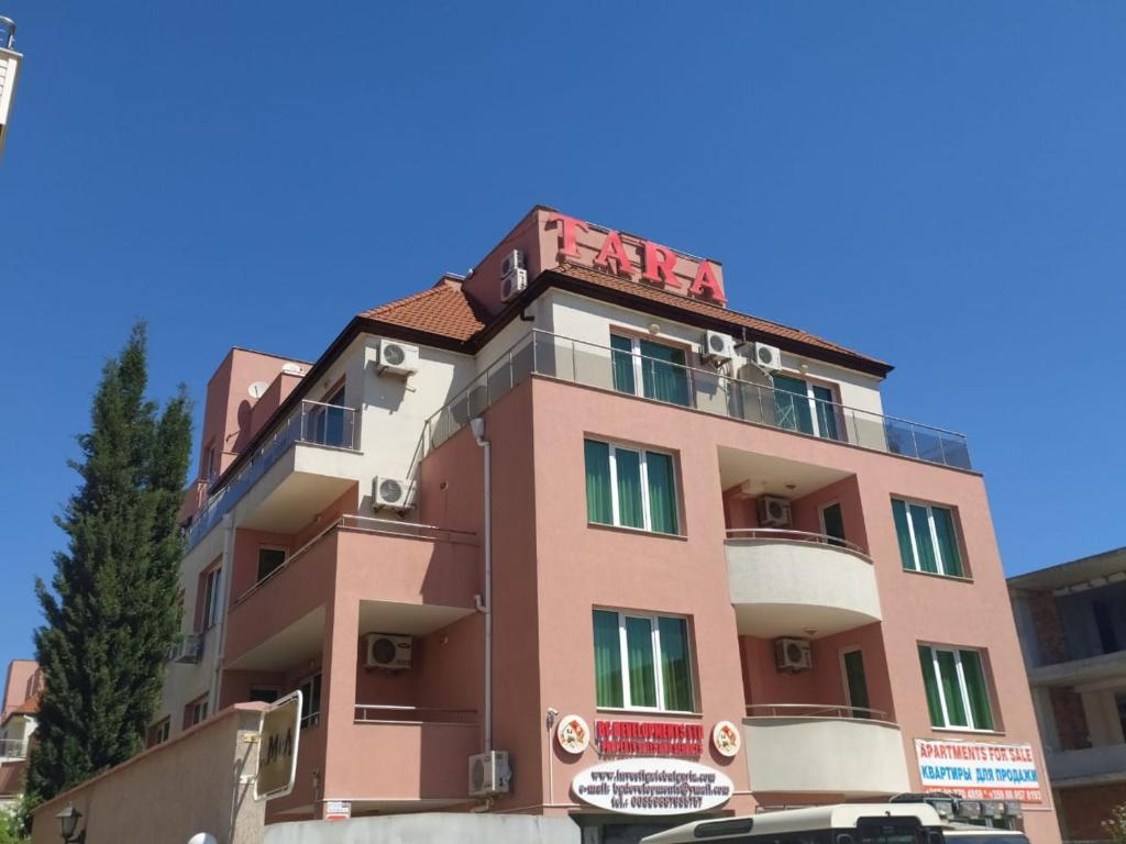 un edificio rosa con sopra un cartello rosso di Apartment in Complex TARA a Ravda