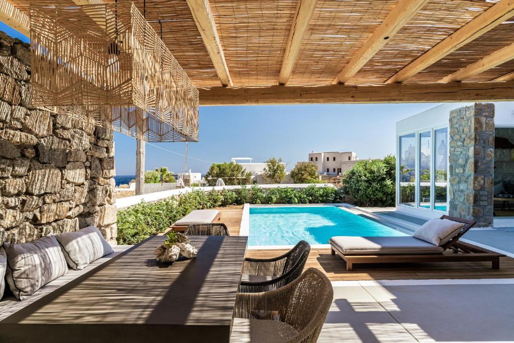 a patio with a table and chairs and a swimming pool at Villa Ananta Mykonos in Mikonos