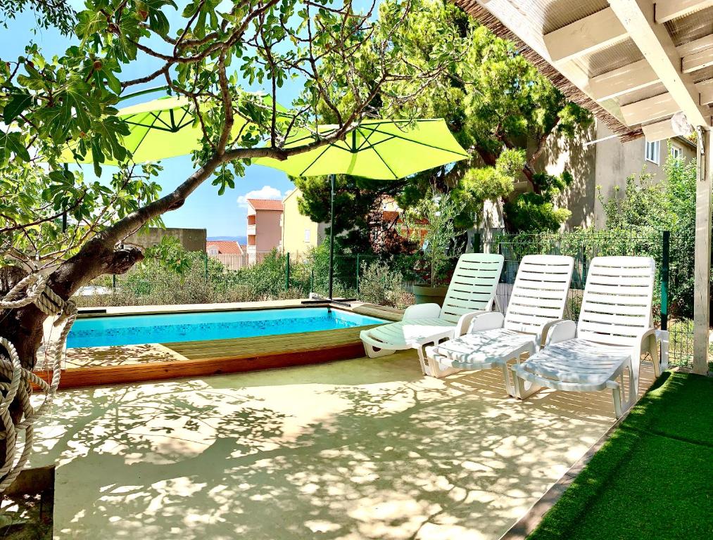 a pool with two lawn chairs and an umbrella at Summer Apartment in Makarska