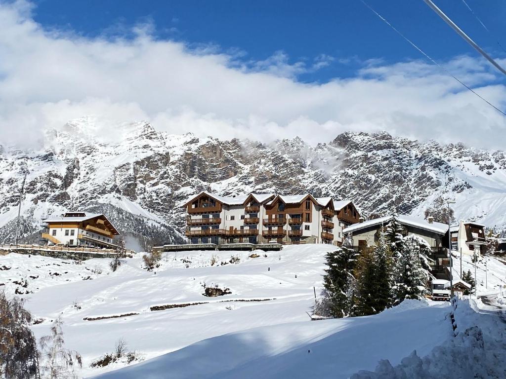 un lodge de esquí con nieve en las montañas en Ai Suma Residence en Bormio