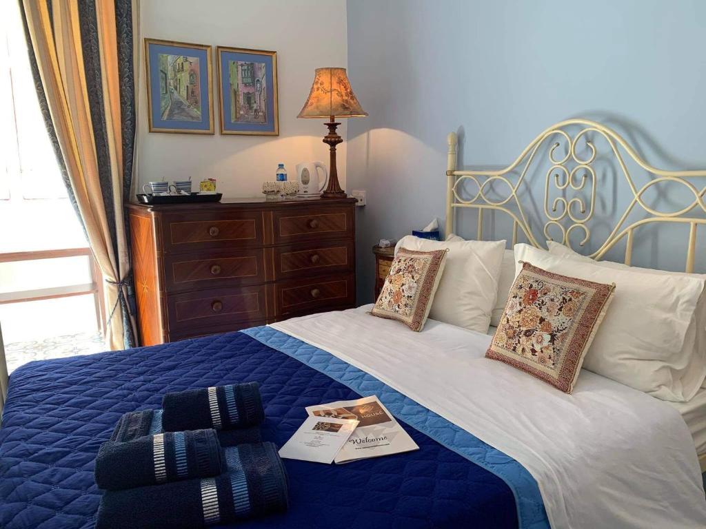 um quarto com uma cama com um cobertor azul e almofadas em Santa Marija House em Victoria