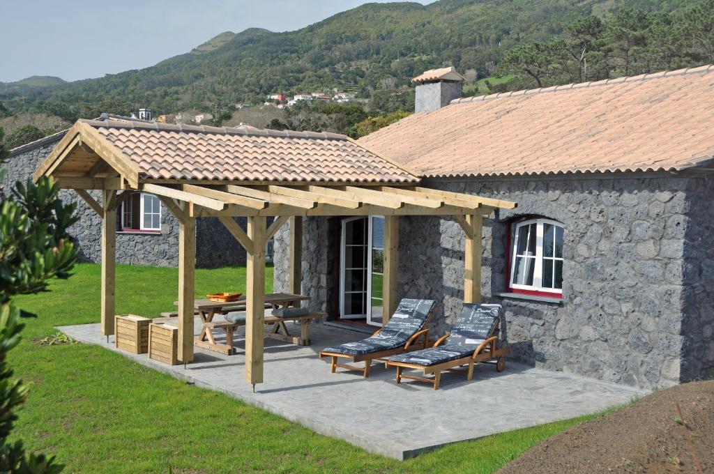 einem Holzpavillon mit Stühlen und einem Tisch vor einem Haus in der Unterkunft Azorenhaus am Atlantik - Family House in Urzelina