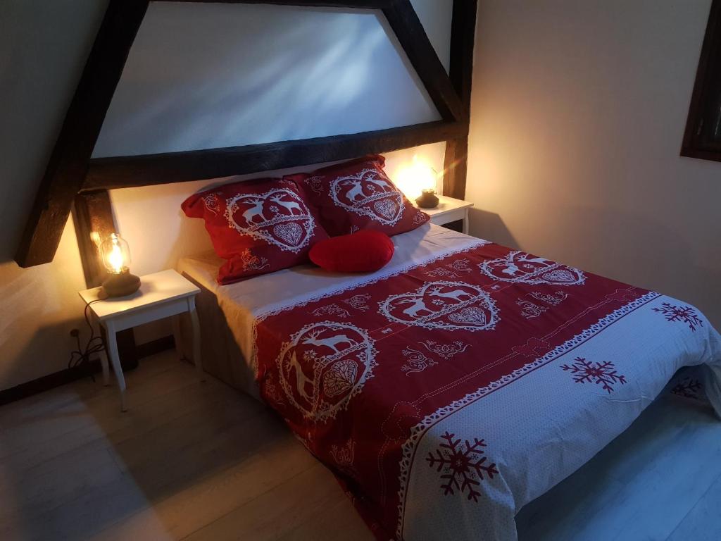 Un dormitorio con una cama con sábanas y almohadas rojas y blancas. en Orée du Bois en Abreschviller