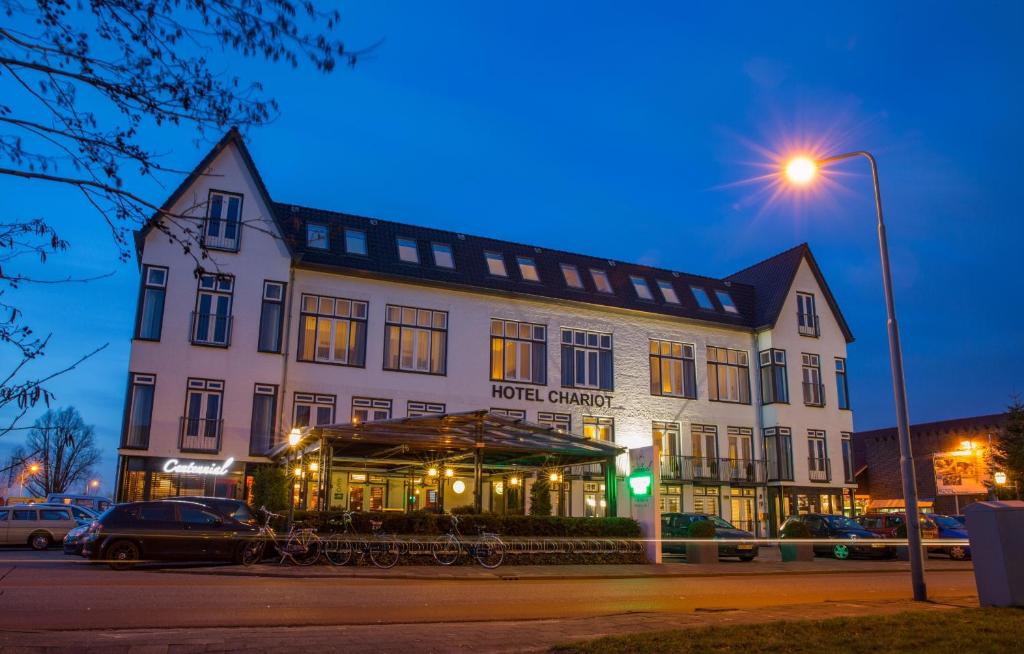 a large white building with a street light in front of it at Boutique Hotel Chariot - Amsterdam Schiphol Airport in Aalsmeer