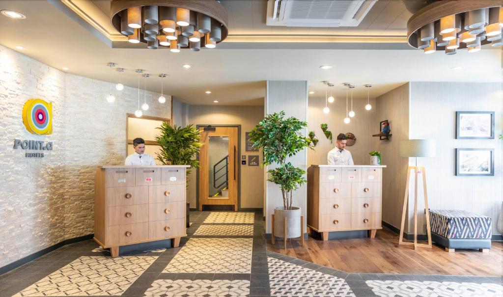 two people are standing in a room with cabinets at Point A Hotel London Paddington in London