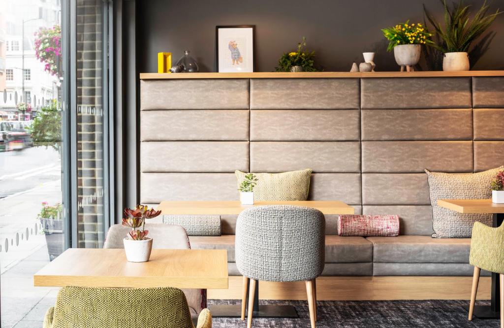 a restaurant with tables and chairs and a couch at Point A Hotel London Paddington in London