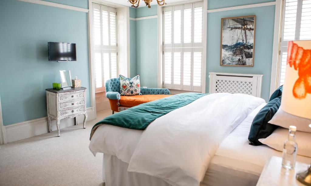 um quarto com paredes azuis e uma cama e uma cadeira em Moore House em Hastings