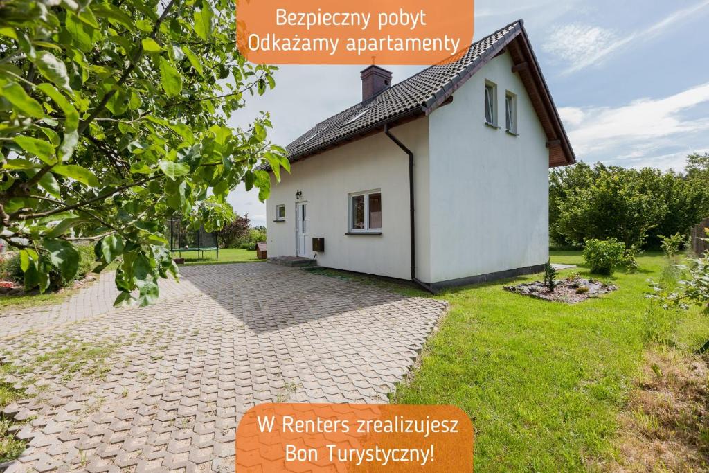 a small white house with a brick driveway at Holiday House Kurnik by Renters in Kołczewo