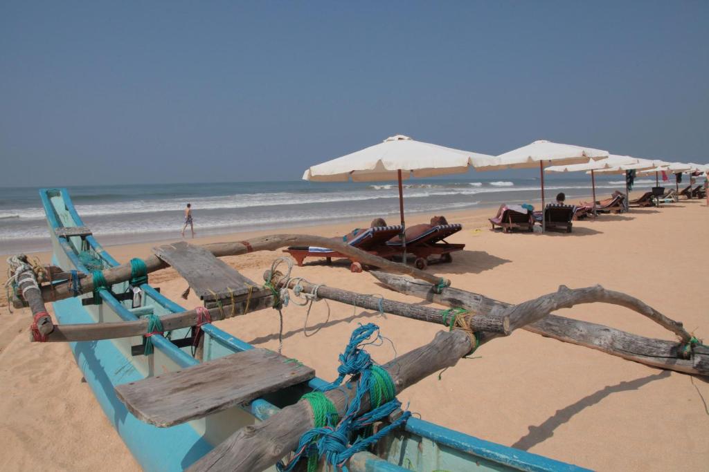 una playa con sombrillas y gente sentada en la playa en Wunderbar Beach Hotel, en Bentota