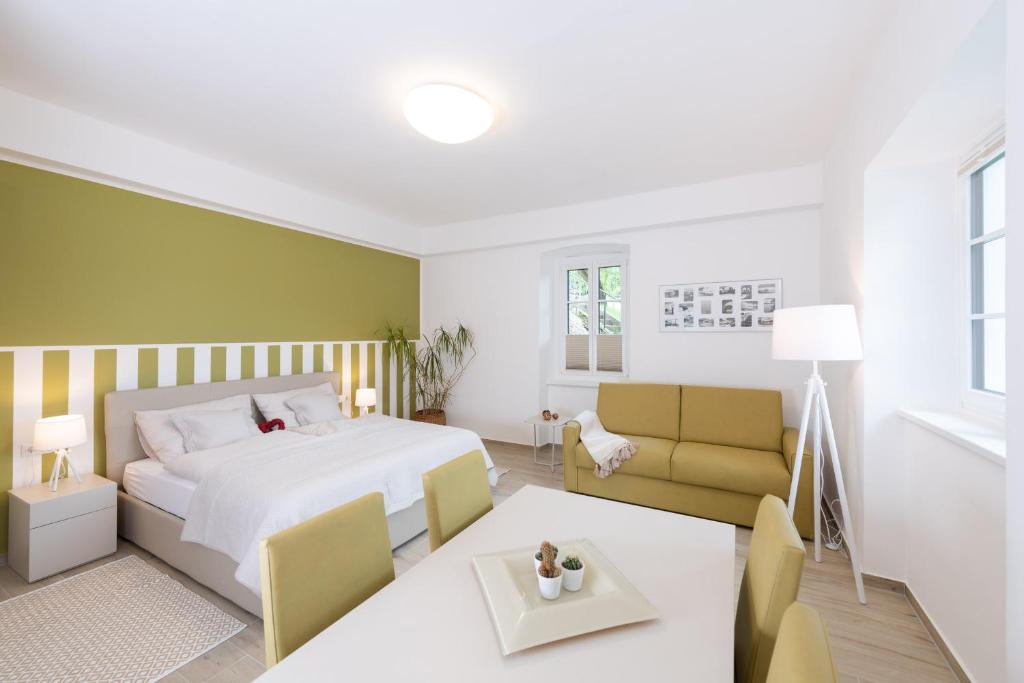 una camera con letto, tavolo e divano di Villa Bella Vista - Apartment Green a Pörtschach am Wörthersee