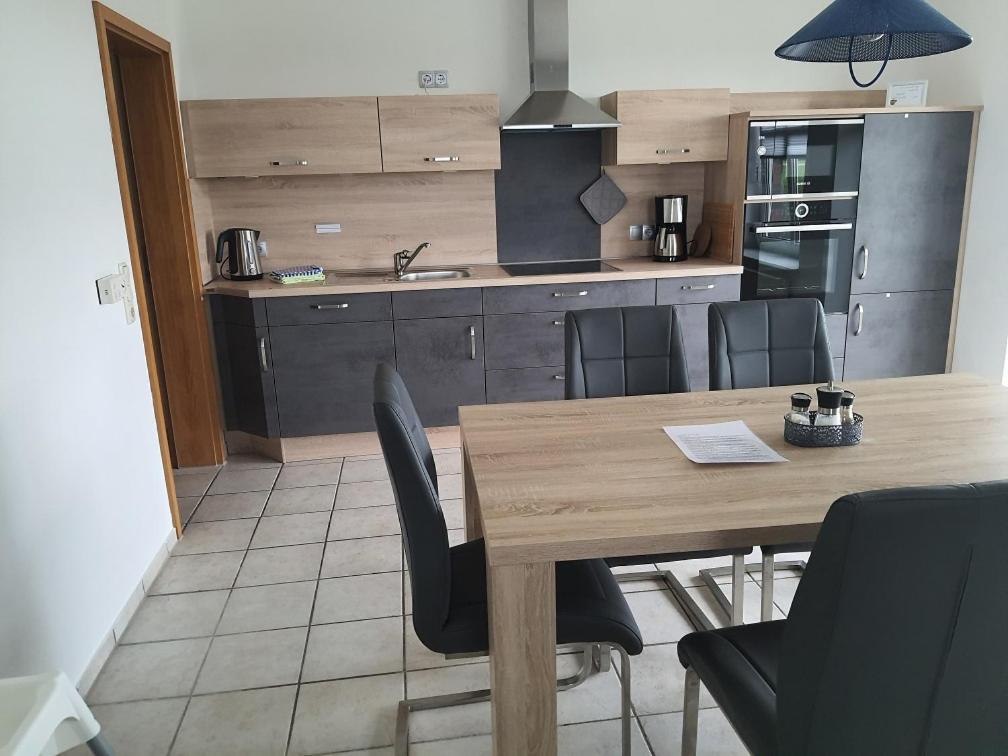 a kitchen with a wooden table and black chairs at Landsitz Riekenshof in Horumersiel in Wangerland