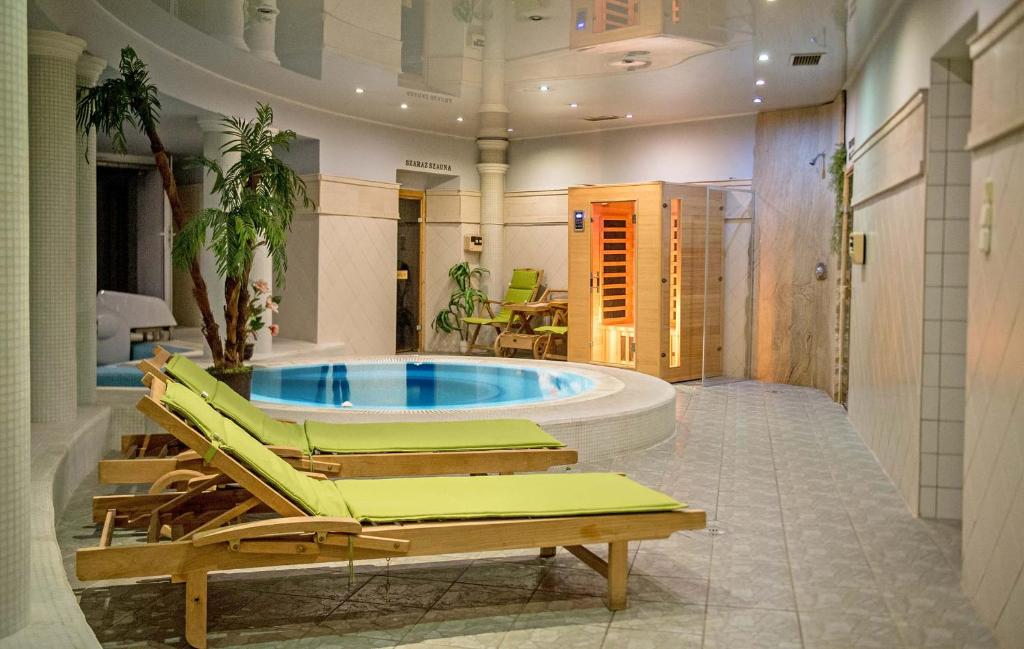 a hot tub in a room with lounge chairs at Hozam Wellness és Apartman in Szolnok