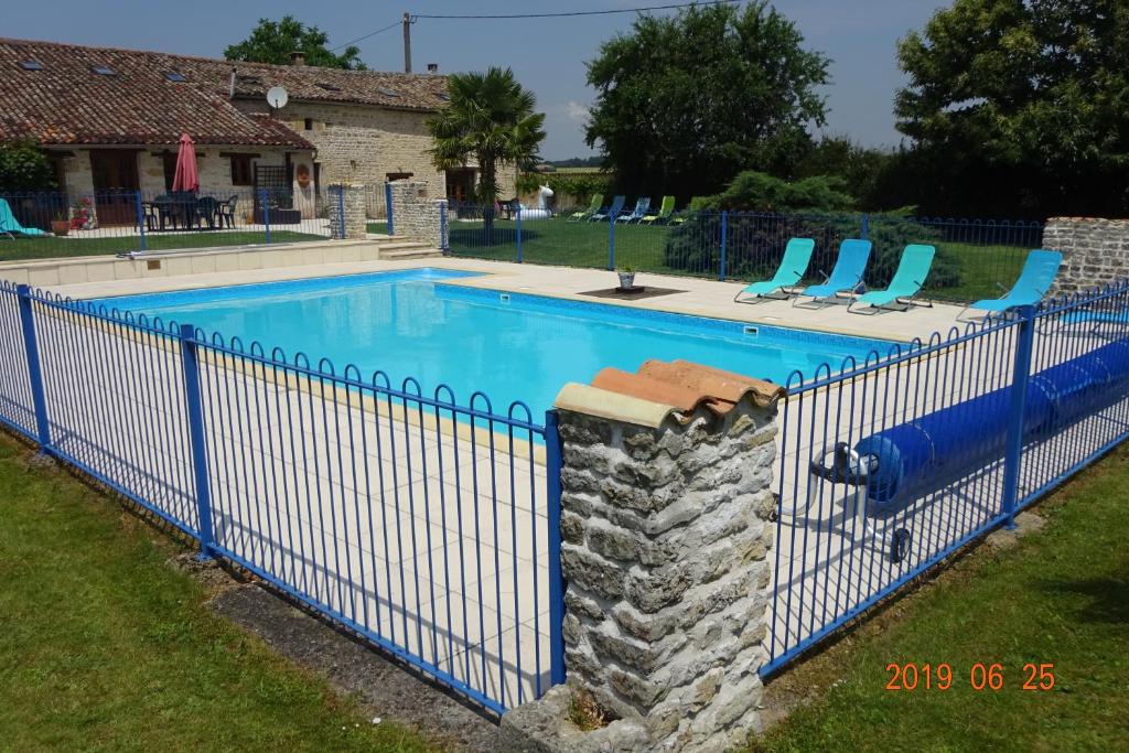 una valla azul alrededor de una piscina con sillas en Chatenet, en Sauzé-Vaussais