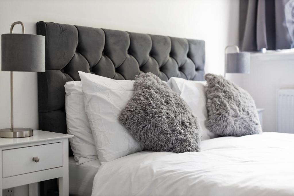 un letto con cuscini bianchi e testiera grigia di The Spinney - Perfect for Contractors, Large Groups & Families a Wolverhampton