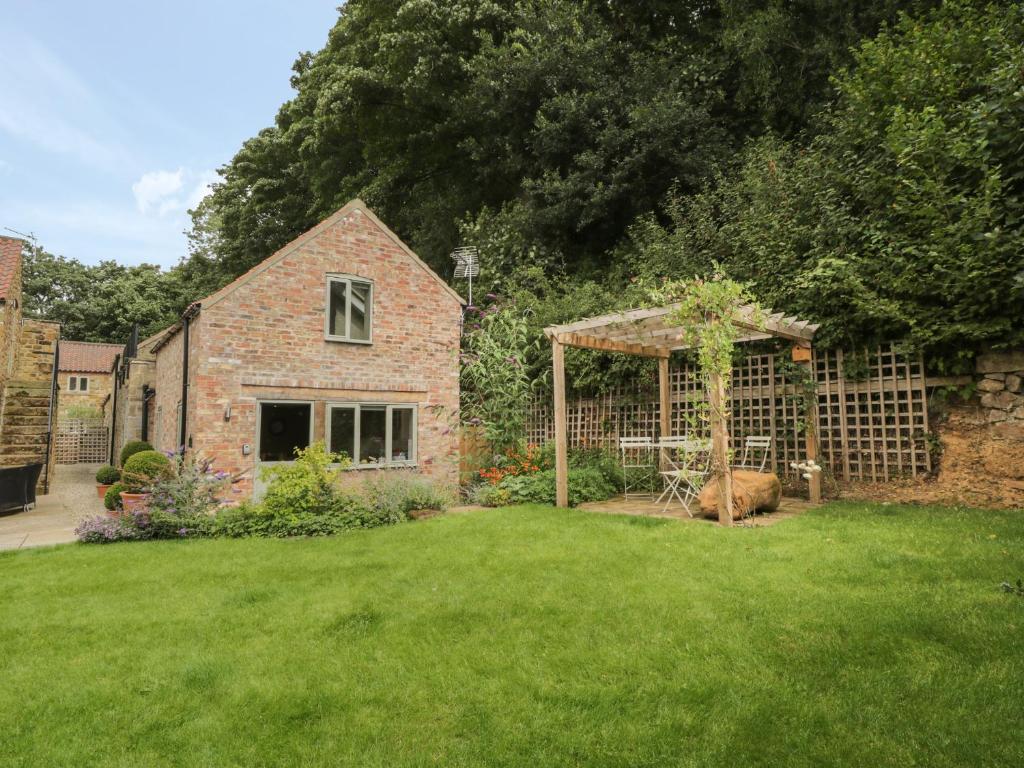 a garden with a brick house with a gazebo at Gormire Cottage in Thirsk