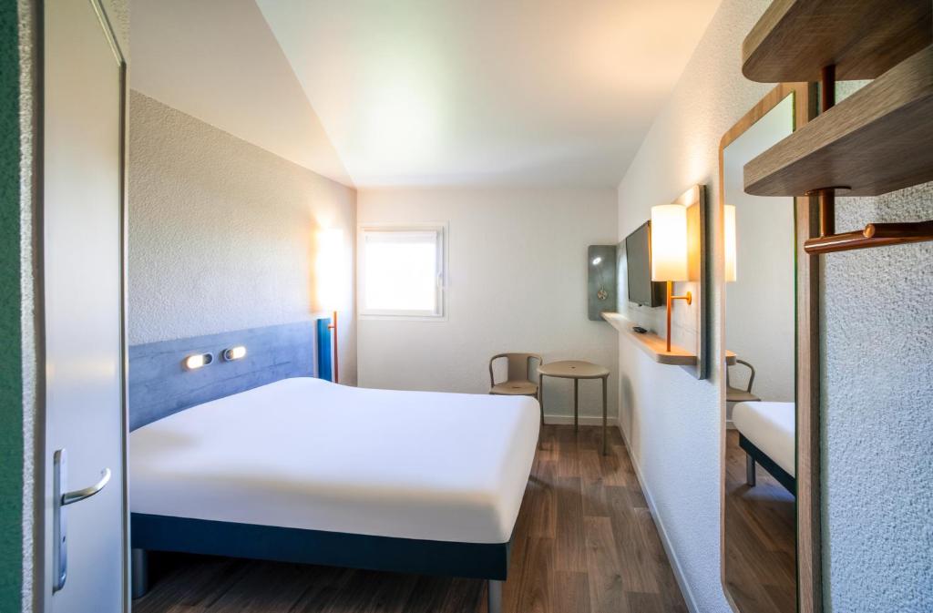 Kleines Zimmer mit einem weißen Bett und einem Fenster in der Unterkunft ibis budget Nuits Saint Georges in Nuits-Saint-Georges