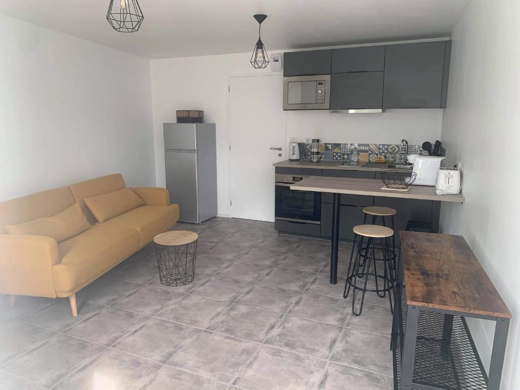 cocina y sala de estar con sofá y mesa en Petite maison charmante en baie de Saint-Brieuc entre Paimpol et Erquy Wifi et parking gratuit en Ploufragan
