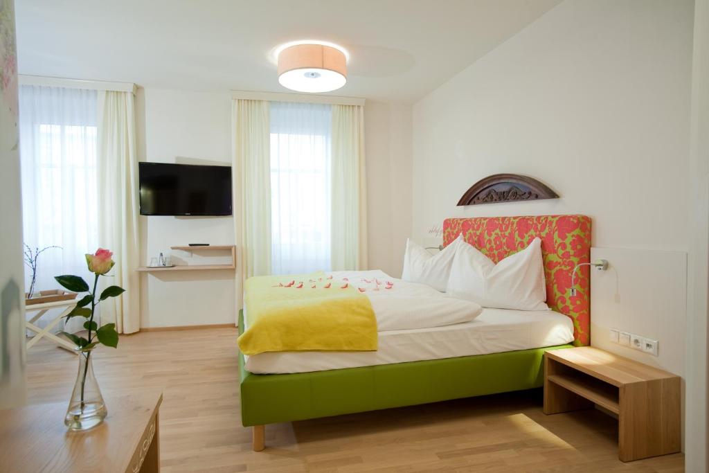 ein Schlafzimmer mit einem großen Bett und einer gelben Decke in der Unterkunft Gasthof Restaurant Zum Brauhaus in Hartberg