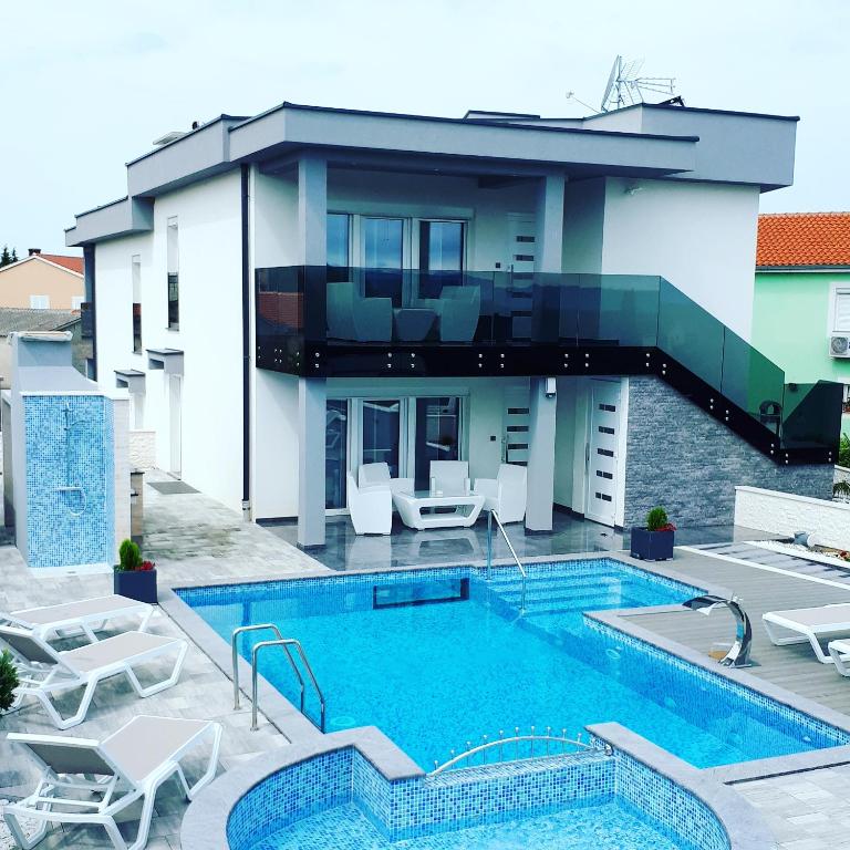 a villa with a swimming pool in front of a house at LUXURY VILLA BEGANOVIC-VRH in Vrh
