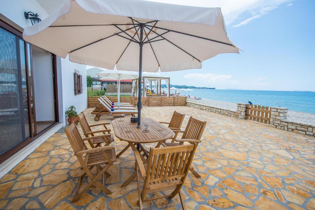 einen Tisch und Stühle mit Sonnenschirm am Strand in der Unterkunft Abraham Apartments in Acharavi