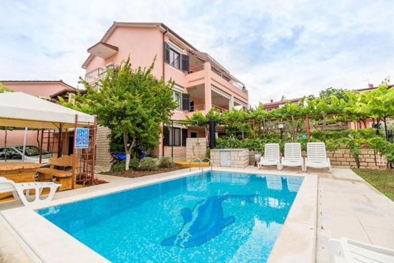 a swimming pool in front of a house at Apartment Pula, Istria 18 in Veli Vrh
