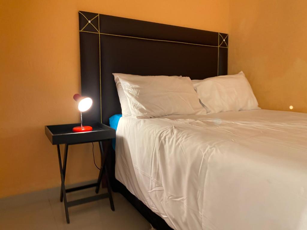 ein Bett mit einem schwarzen Kopfteil und einem Beistelltisch mit einer Lampe in der Unterkunft Mankweng lodge in Polokwane