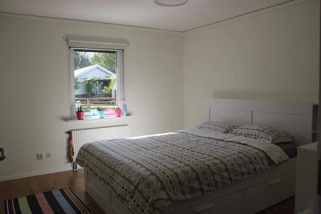 a white bedroom with a bed and a window at Private room for rent in a villa with garden view in Älmhult