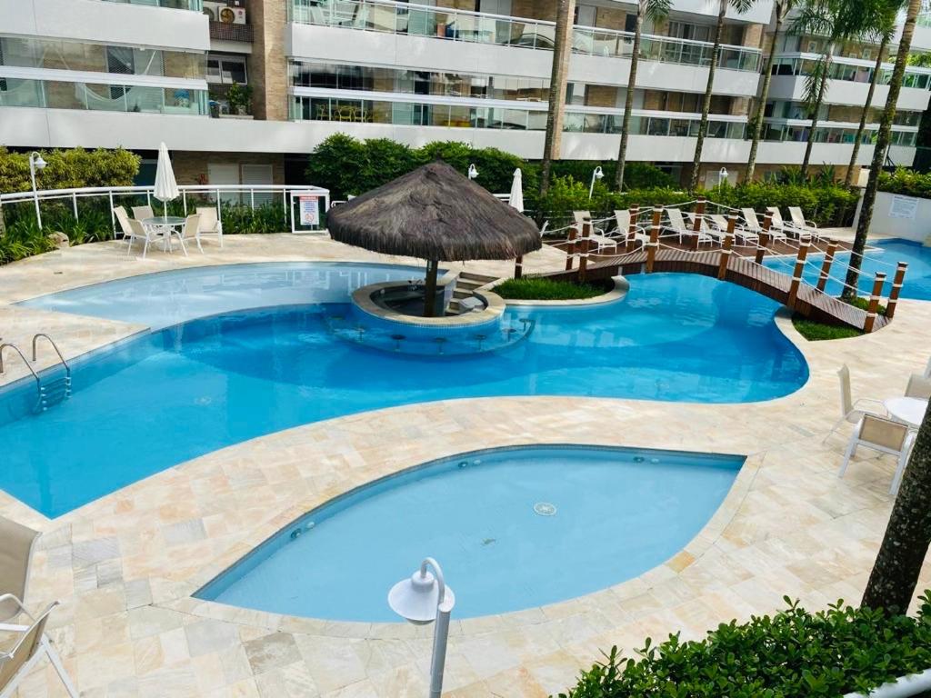 une grande piscine bleue avec un parasol et des chaises dans l'établissement Apartamento Alto Padrão - Home Resort Laguna, à Riviera de São Lourenço