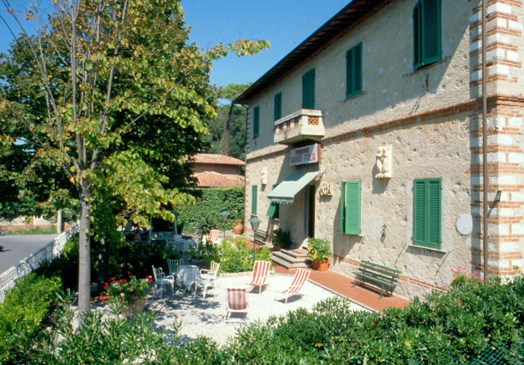 een gebouw met een patio met stoelen en een boom bij Albergo Grande Italia in Marina di Pietrasanta