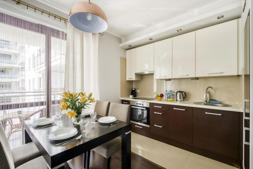 eine Küche mit weißen Schränken und einem Tisch mit Stühlen in der Unterkunft MG Apartments Giełdowa in Warschau