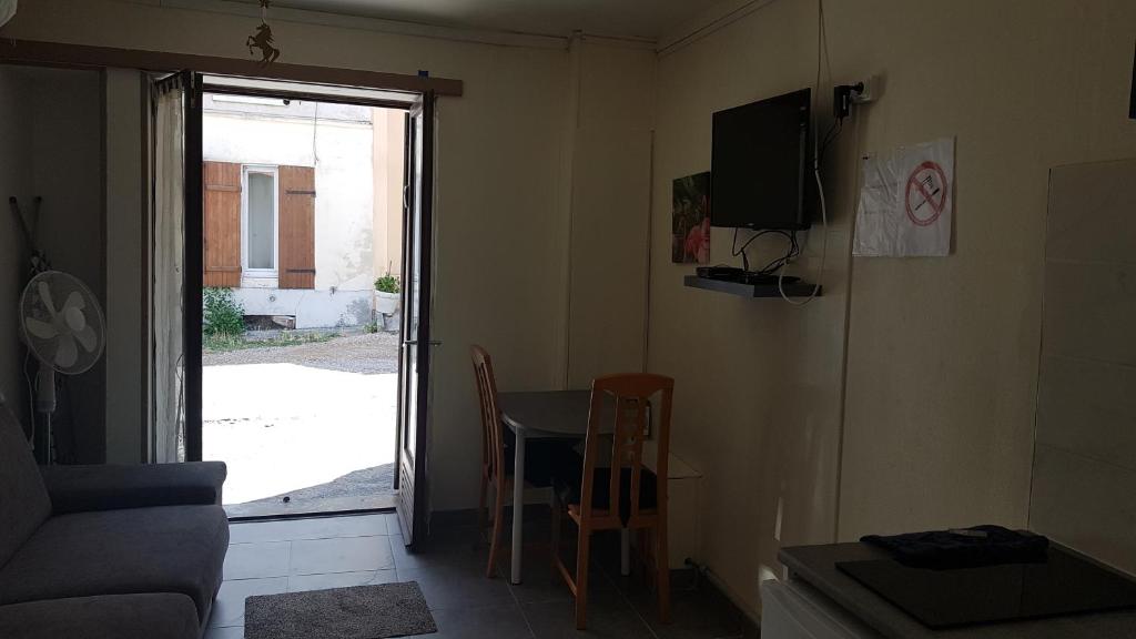 a living room with a table and a tv on the wall at Joli studio proche de DisneyLand Paris in Nanteuil-lès-Meaux