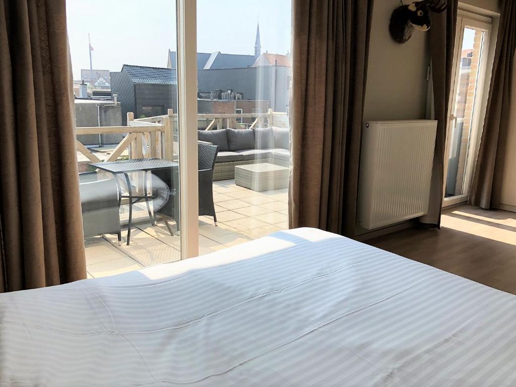 een slaapkamer met een bed en uitzicht op een balkon bij Palazzo by Villa Verde -Unique appartment- in De Haan