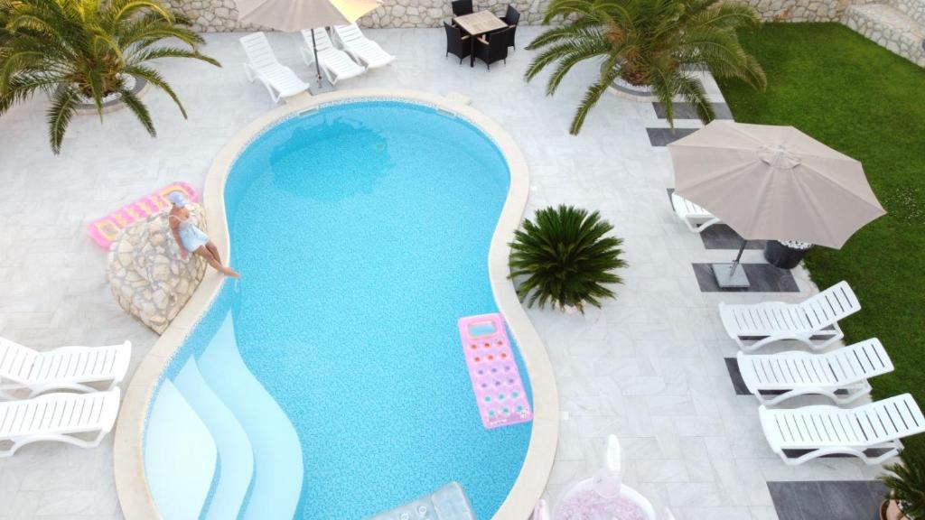 una vista aérea de una piscina con sillas y sombrillas en Apartments Roxsi, en Novalja