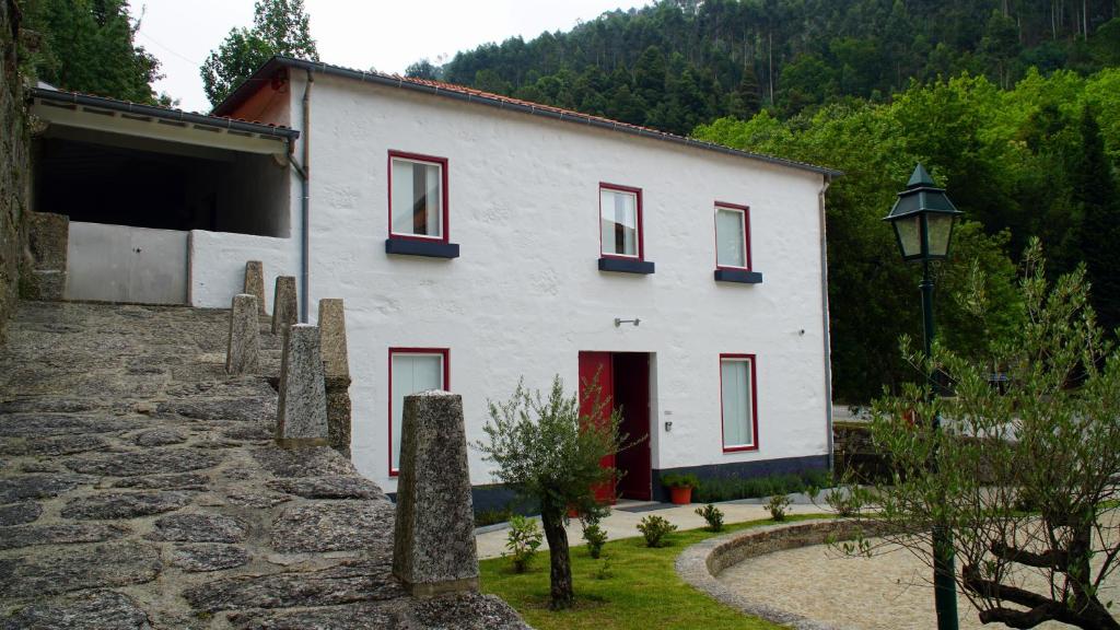 ein weißes Gebäude mit roten Fenstern und einem Straßenlicht in der Unterkunft Casa Abrigo do Lagar in Amares