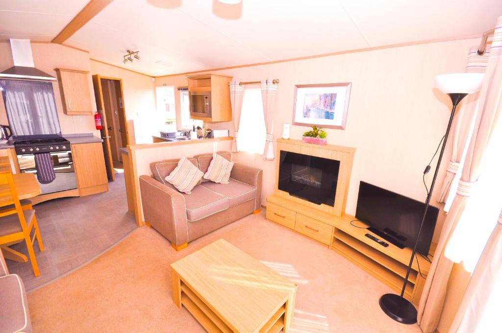 uma sala de estar com um sofá e uma televisão em Caravan by Camber Sands 2 em Camber