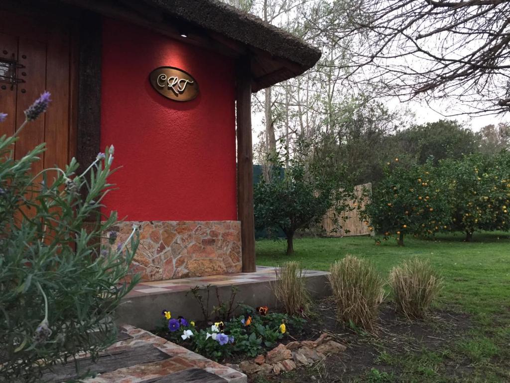 una casa roja con un cartel en el costado. en CABAÑA LA TOSCANA, en Carmelo