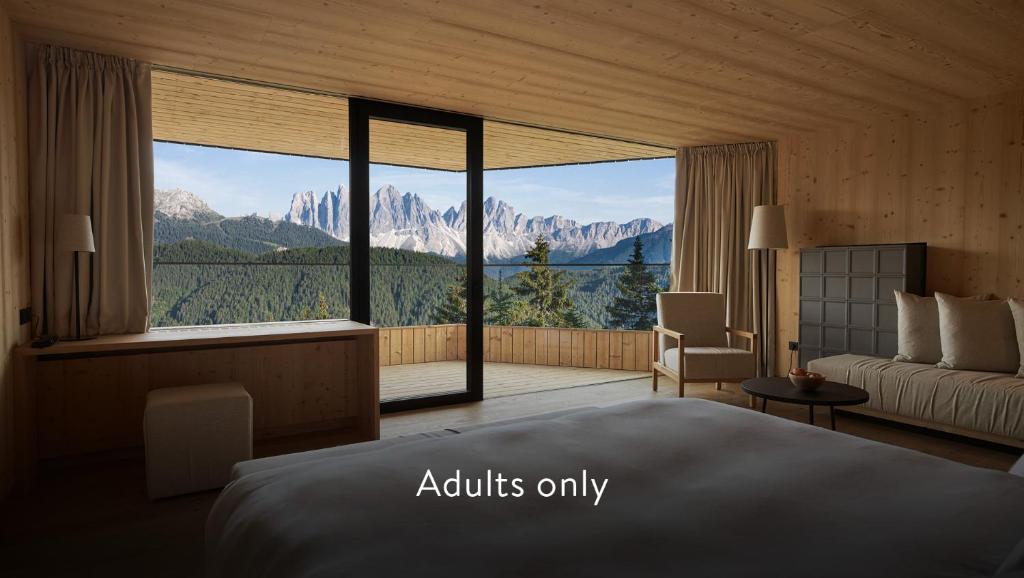 a hotel room with a bed, table and windows at Forestis Dolomites in Bressanone