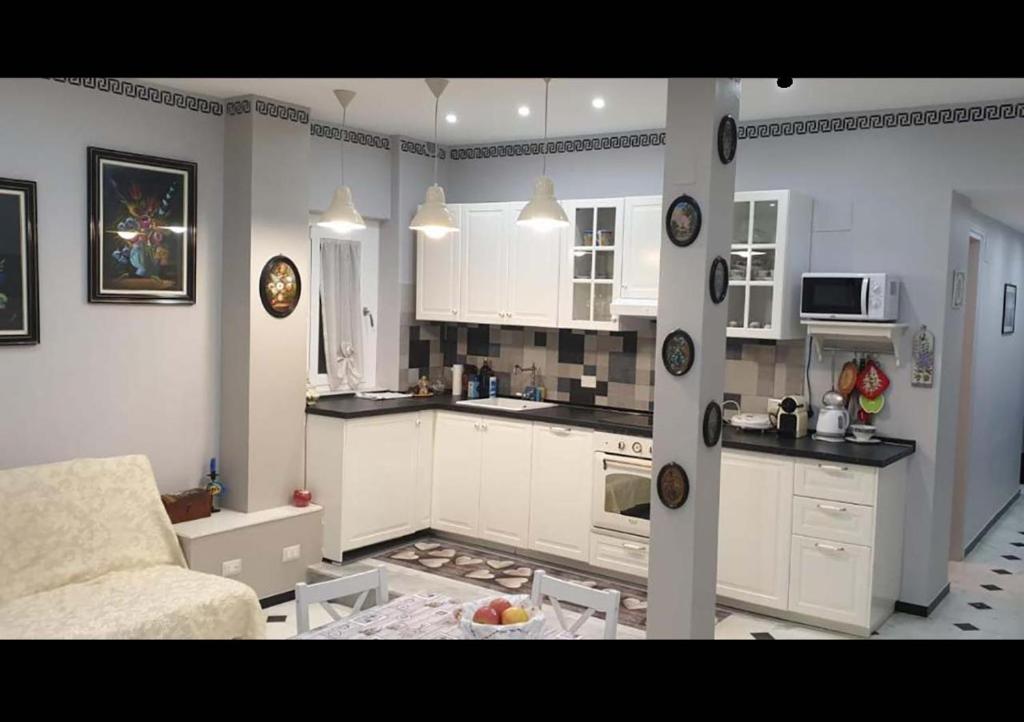eine Küche mit weißen Schränken und ein Wohnzimmer in der Unterkunft Matteotti Apartment in Rapallo