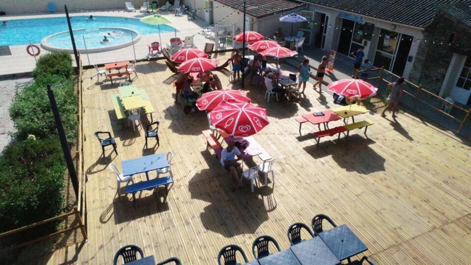 un groupe de tables avec des parasols rouges à côté d&#39;une piscine dans l&#39;établissement Camping le Village de Florine, à Coëx