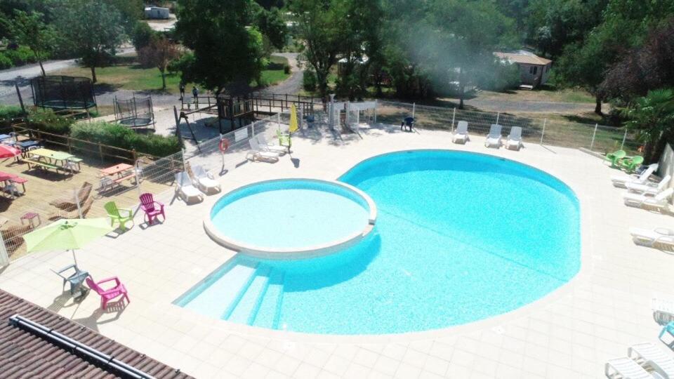une grande piscine bleue avec des chaises et des parasols dans l&#39;établissement Camping le Village de Florine, à Coëx